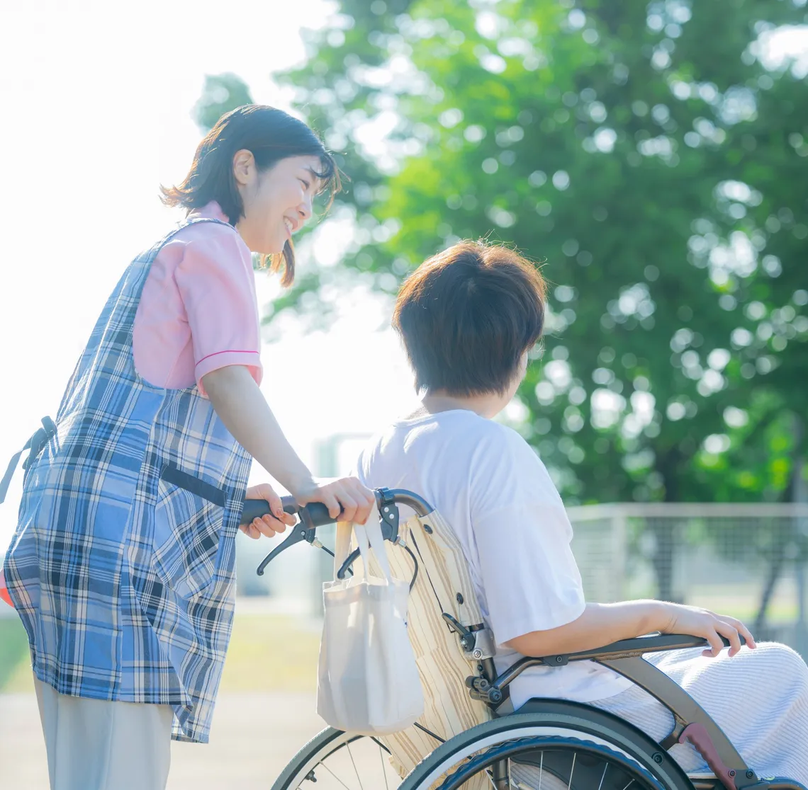 車いすを押して散歩する介護スタッフ