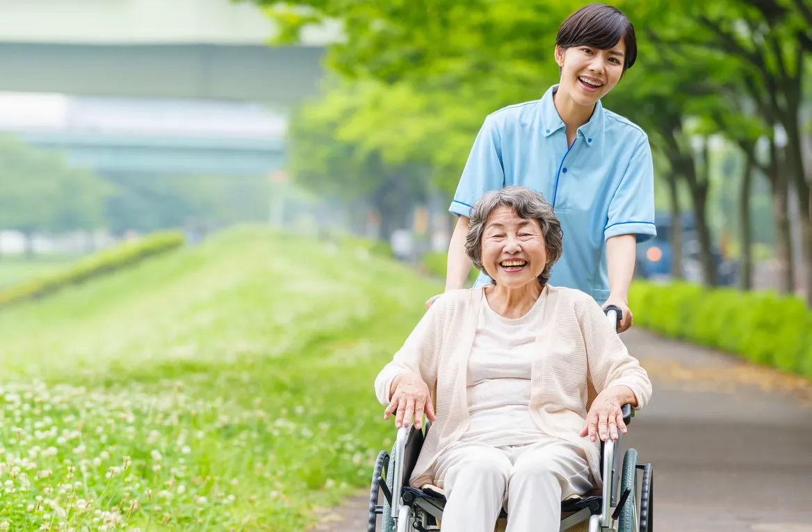 車椅子の高齢女性と笑顔のスタッフの散歩