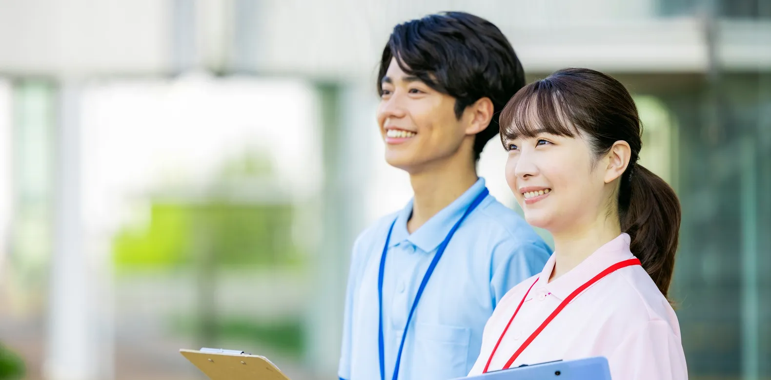 クリップボードを持って微笑むスタッフ2人