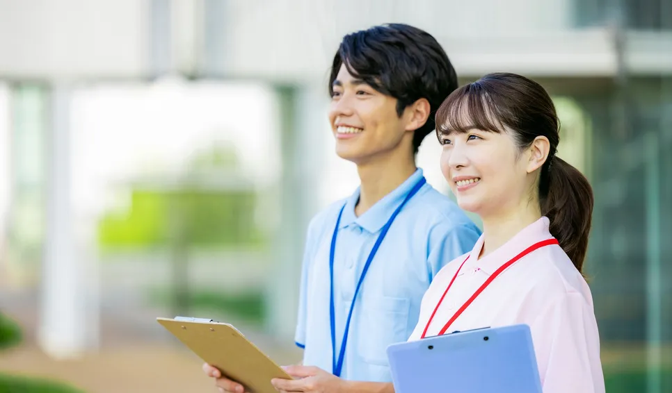 クリップボードを持って微笑むスタッフ2人