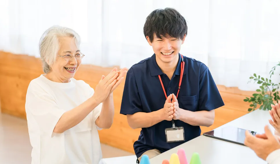笑顔で拍手する高齢女性とスタッフ